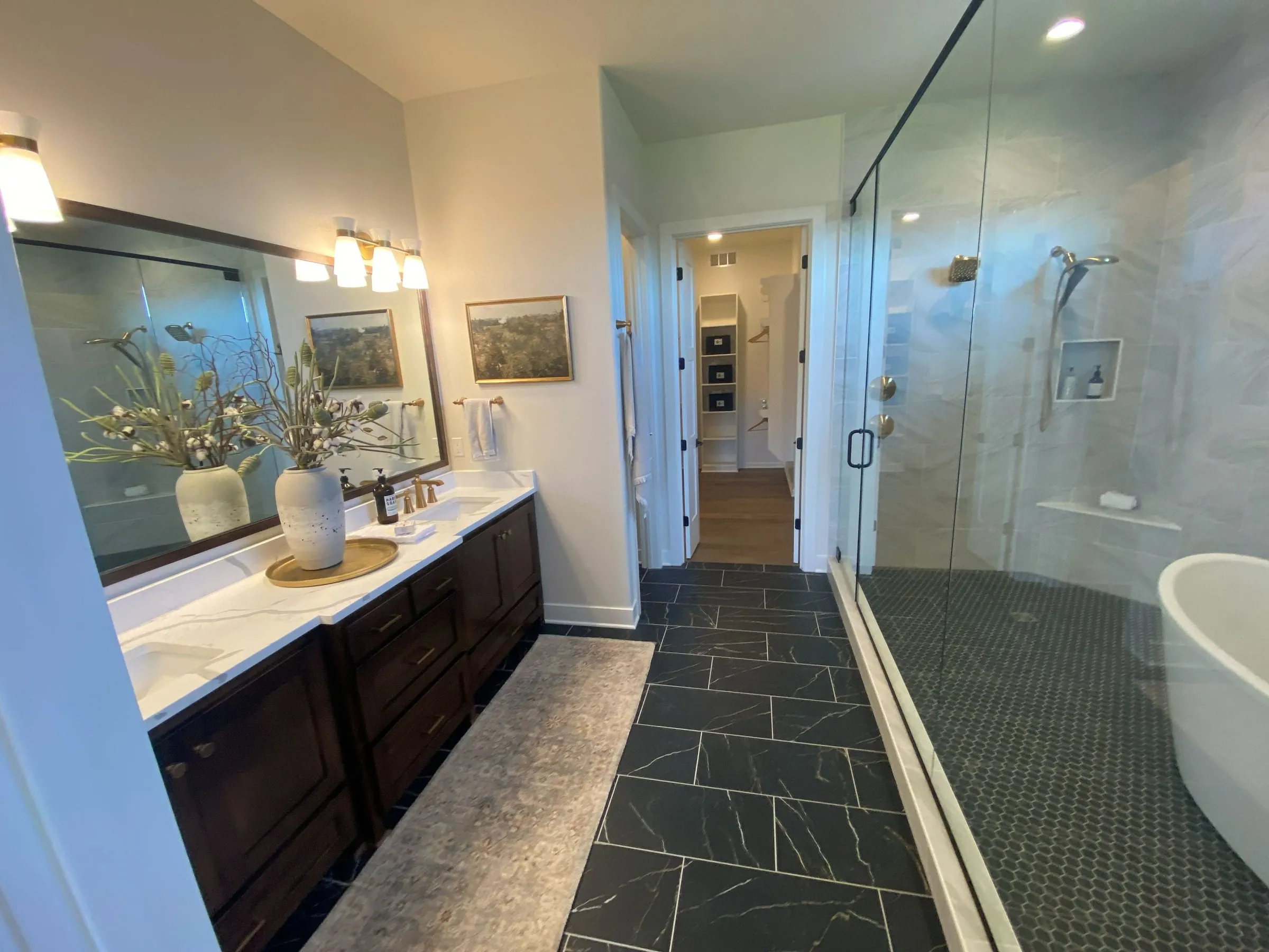 Primary bathroom with a double vanity, slate tile floor, glass shower and soaking tub