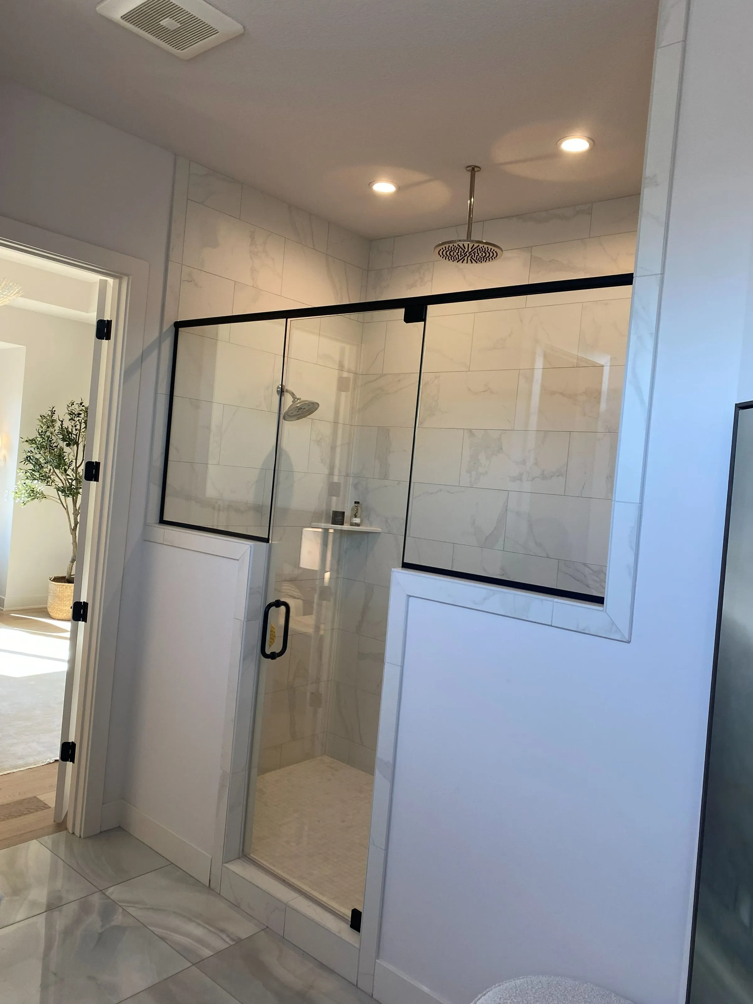 Frameless glass shower with a rain head and black fixtures