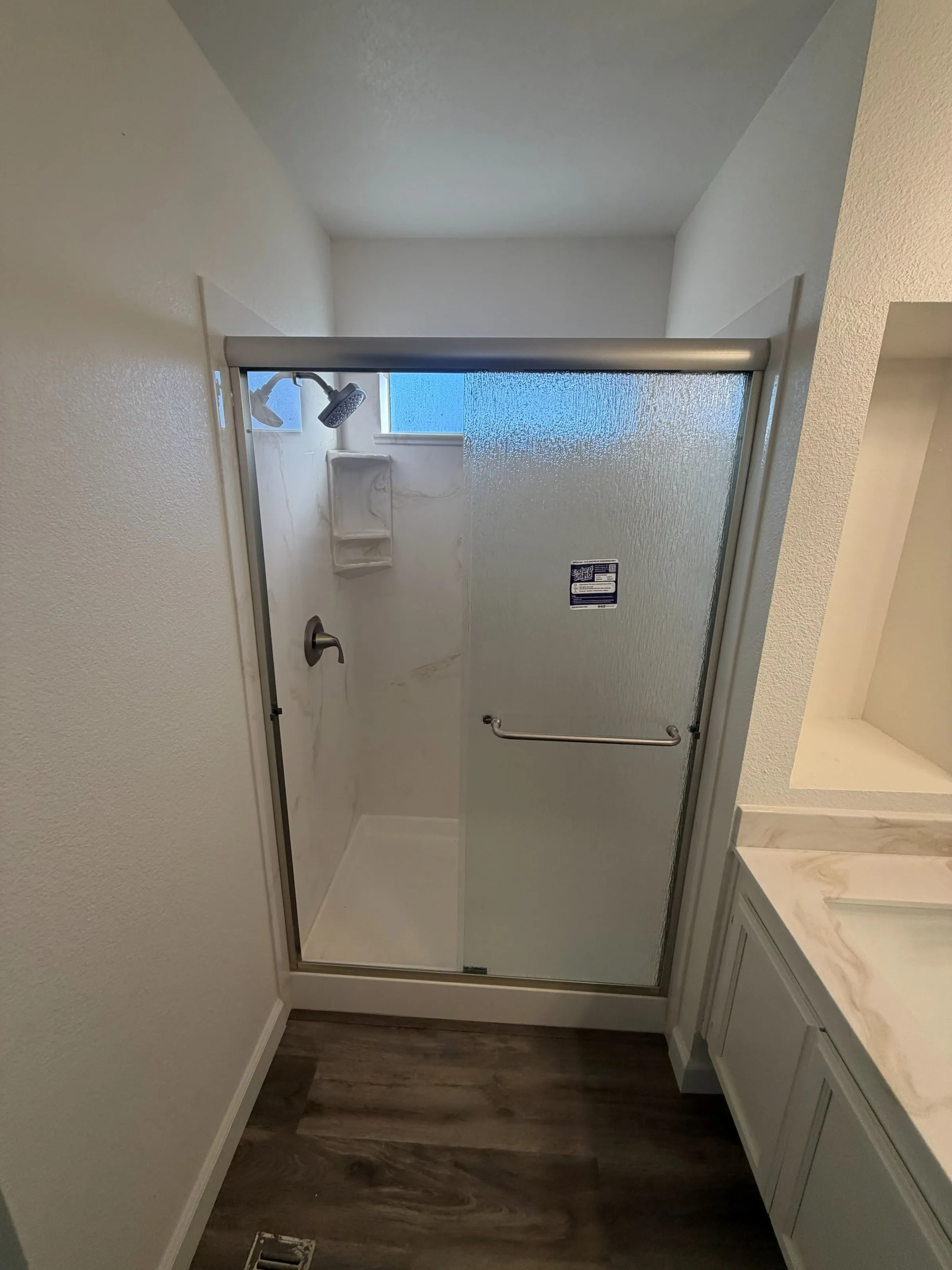 Bathroom remodel with a walk-in shower behind sliding glass doors and a quartz vanity