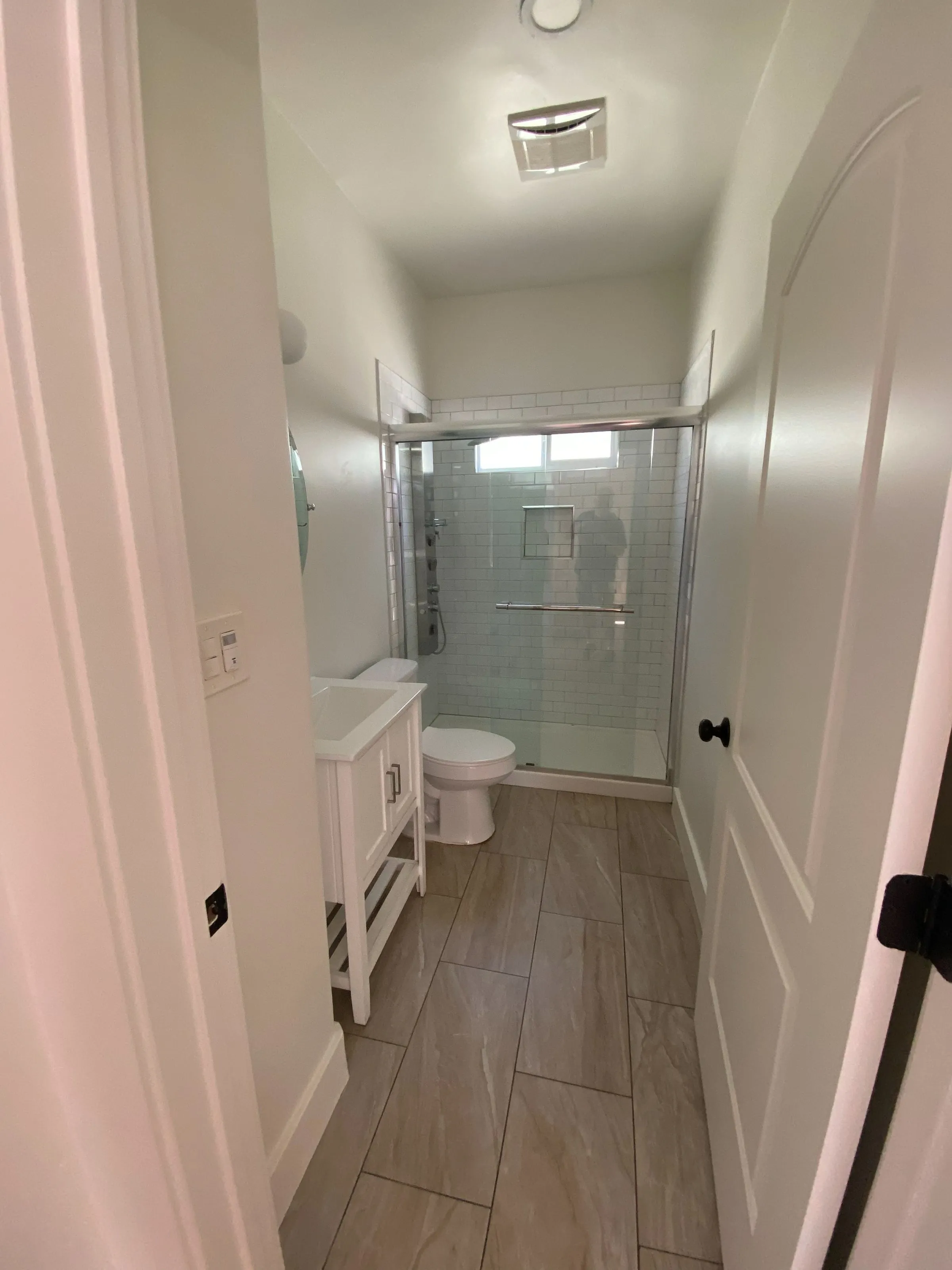 Narrow bathroom remodel with a glass-door shower, compact vanity and wood-look tile