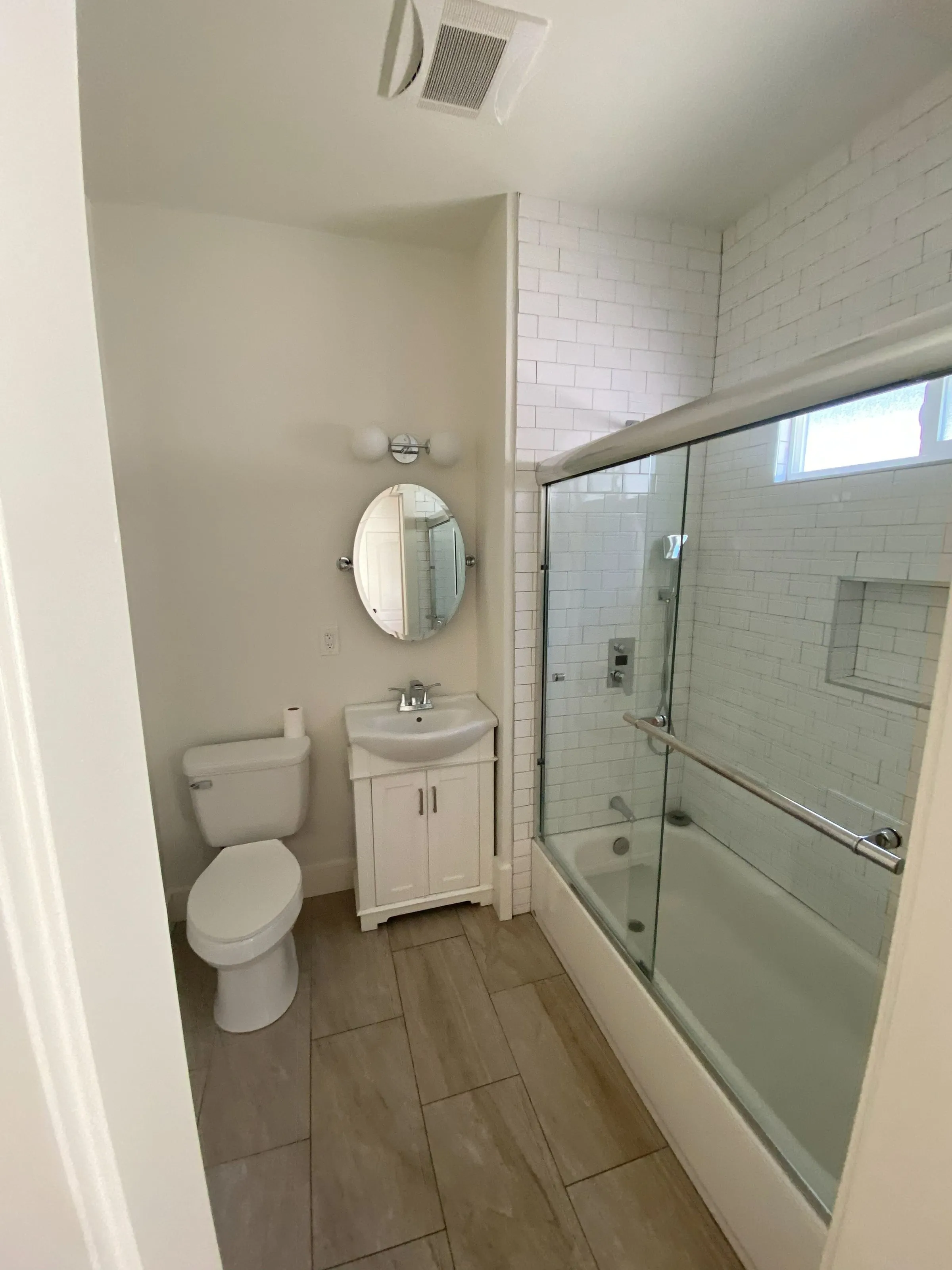 Bathroom remodel with a subway tile tub surround, glass doors and a pedestal-style vanity