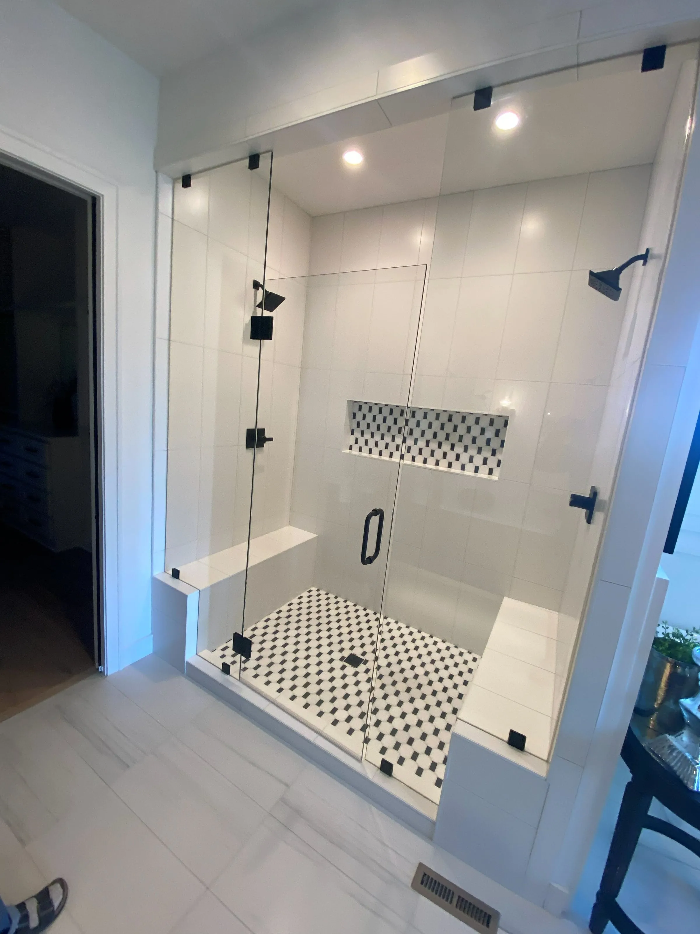 Tiled walk-in shower with a built-in bench, niche and frameless glass enclosure