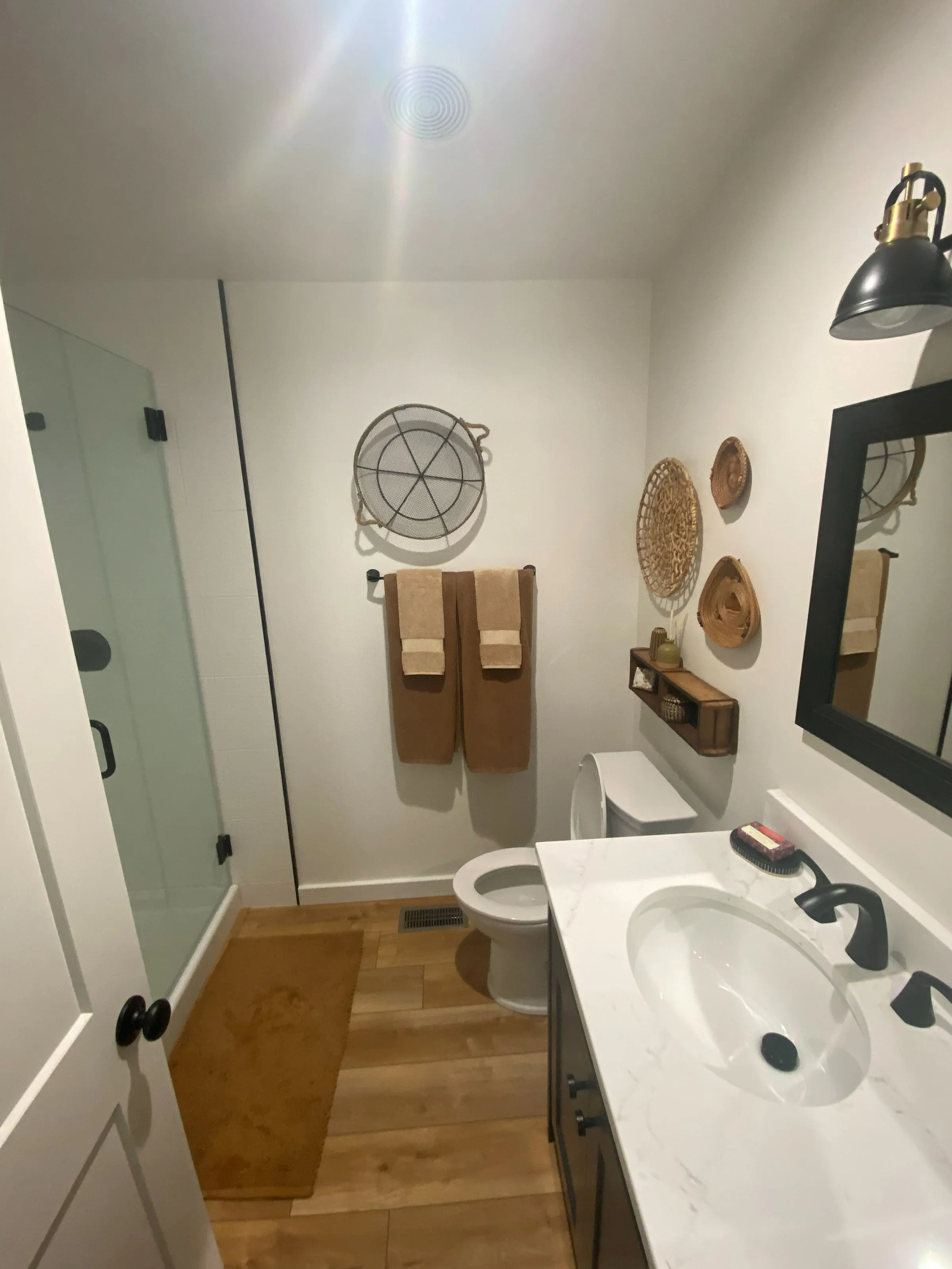 Remodeled bathroom with a white vanity top, black faucet and glass shower door