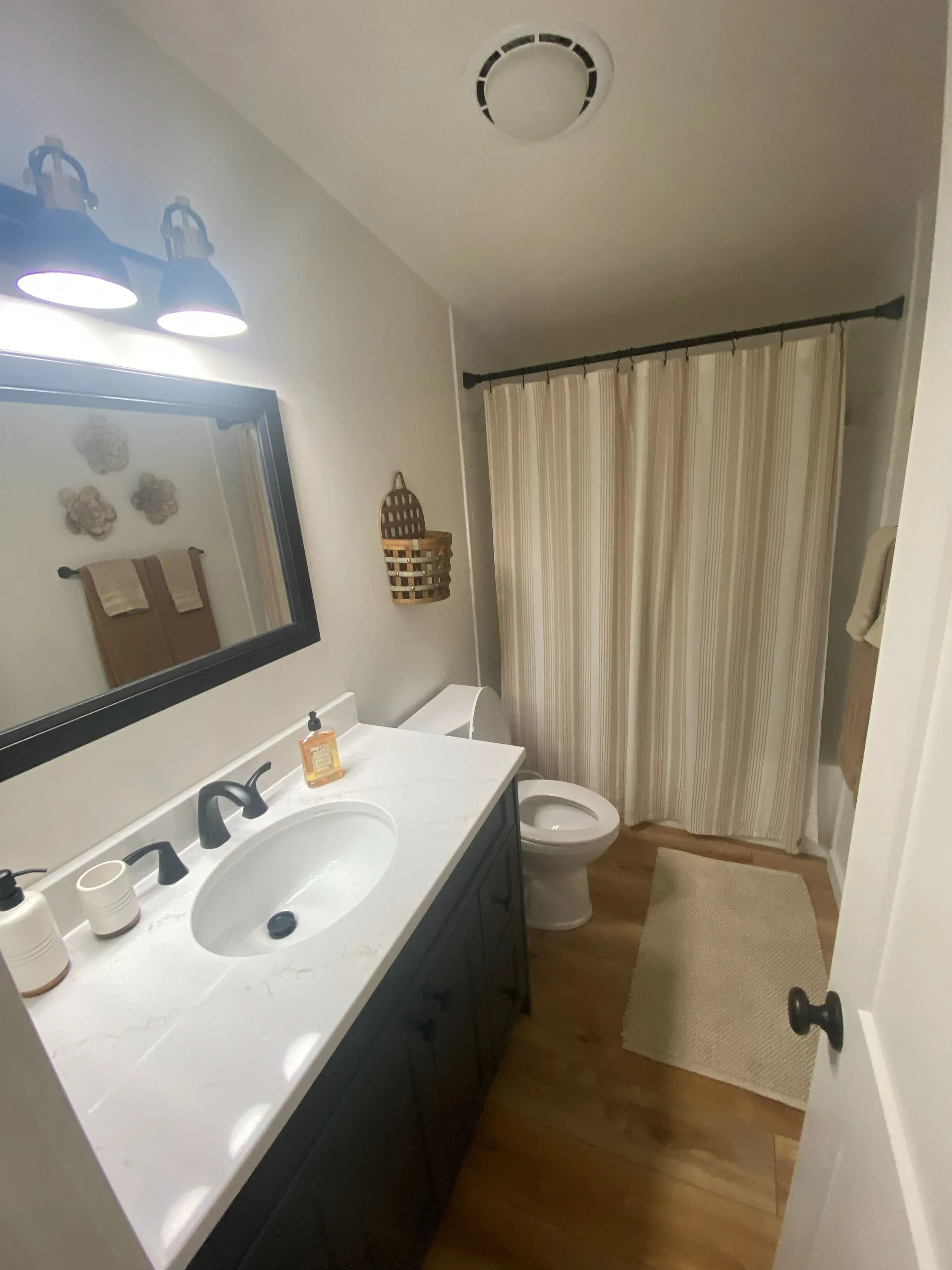 Updated bathroom with a new vanity, framed mirror and light fixture