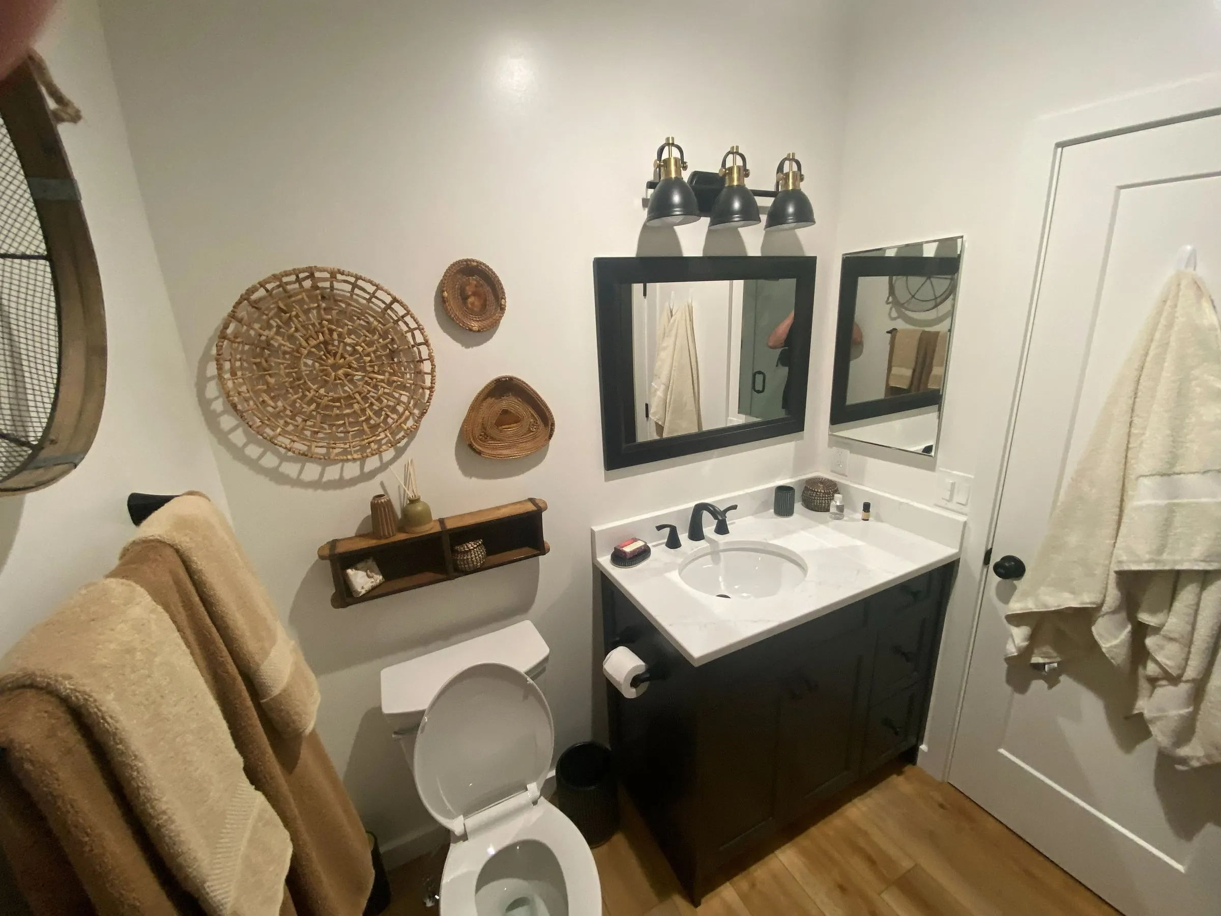 Bathroom remodel with a dark vanity, white countertop, black faucet and new lighting