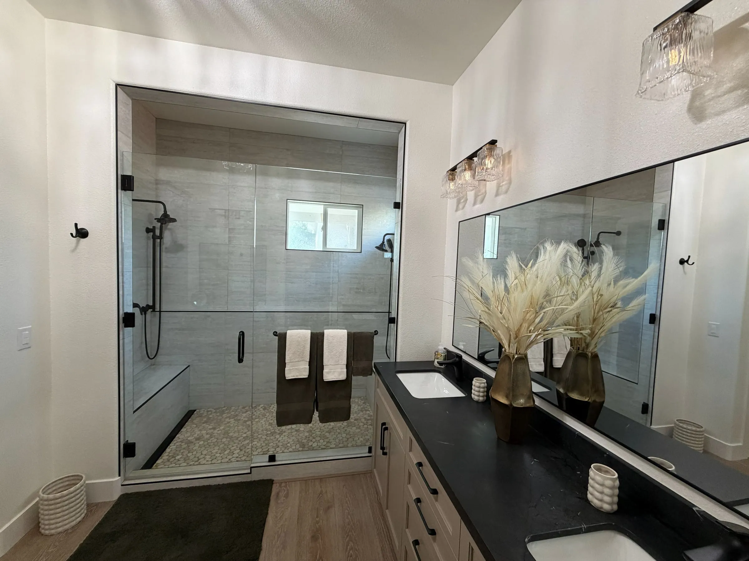 Remodeled bathroom with a walk-in tile shower, frameless glass and a long double vanity