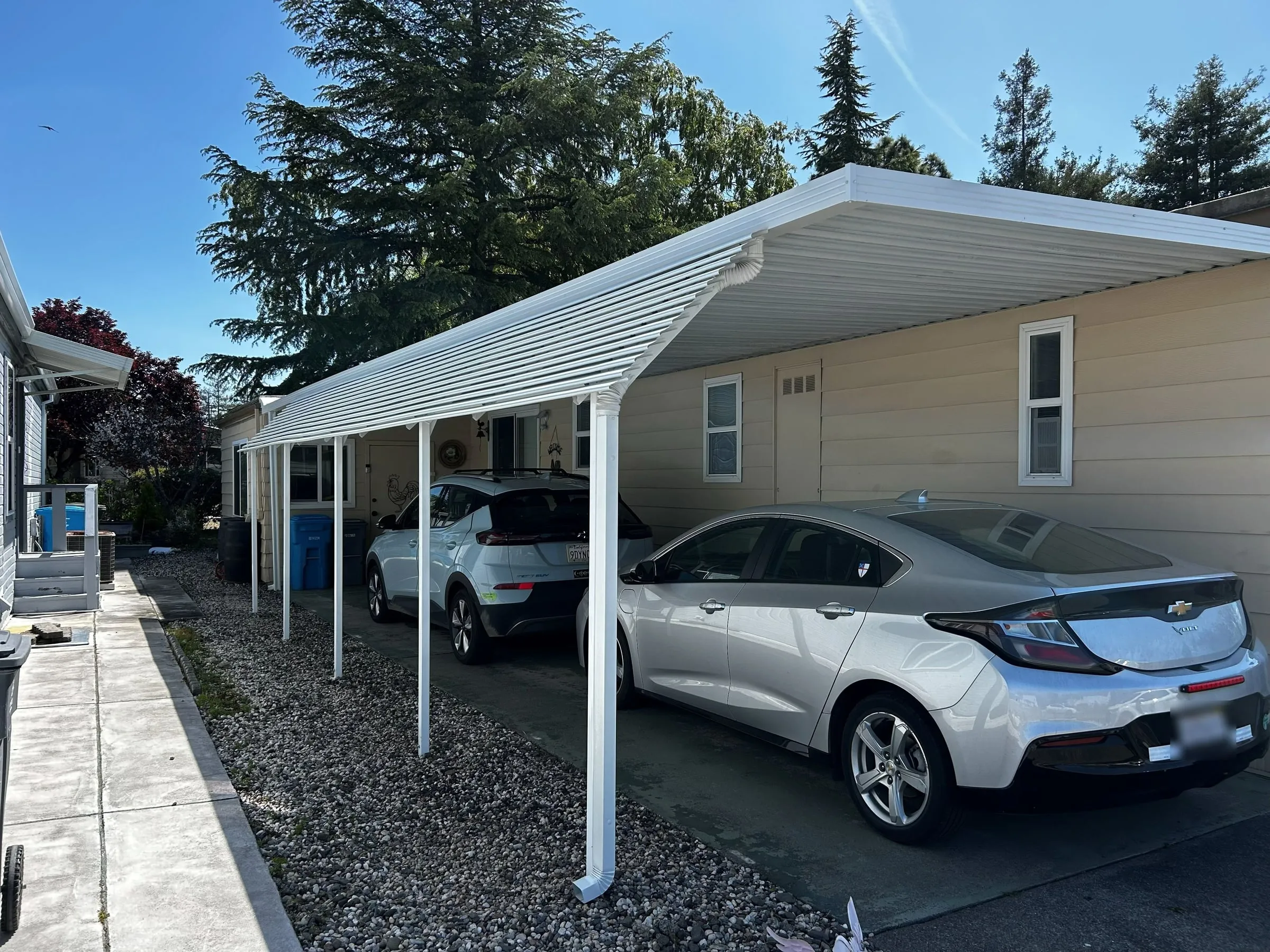 Long aluminum carport over the driveway beside a mobile home