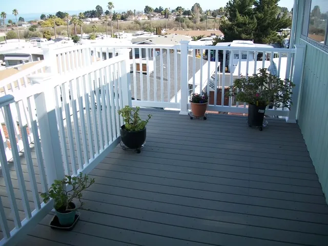 Composite deck with white railings and potted plants at a mobile home