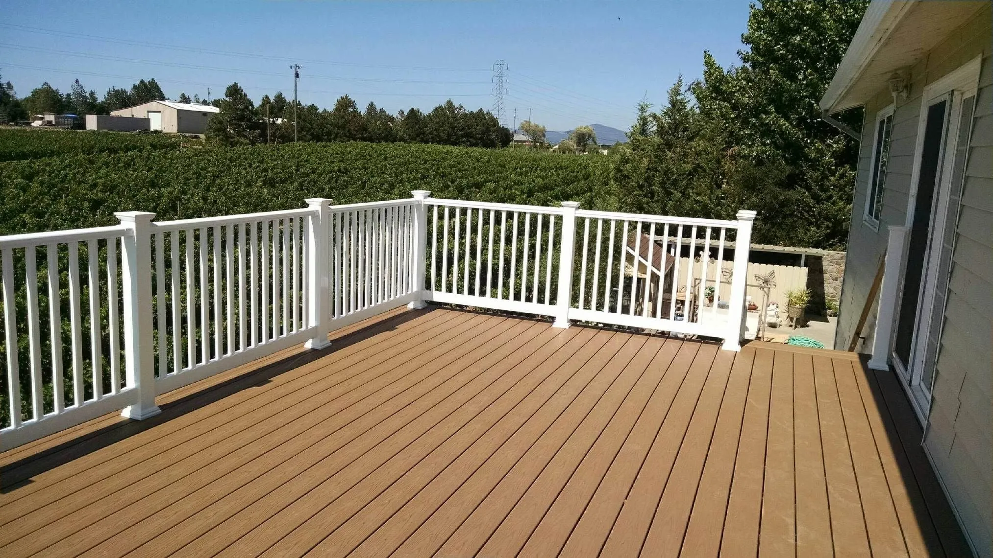 Composite deck with white vinyl railing overlooking a vineyard