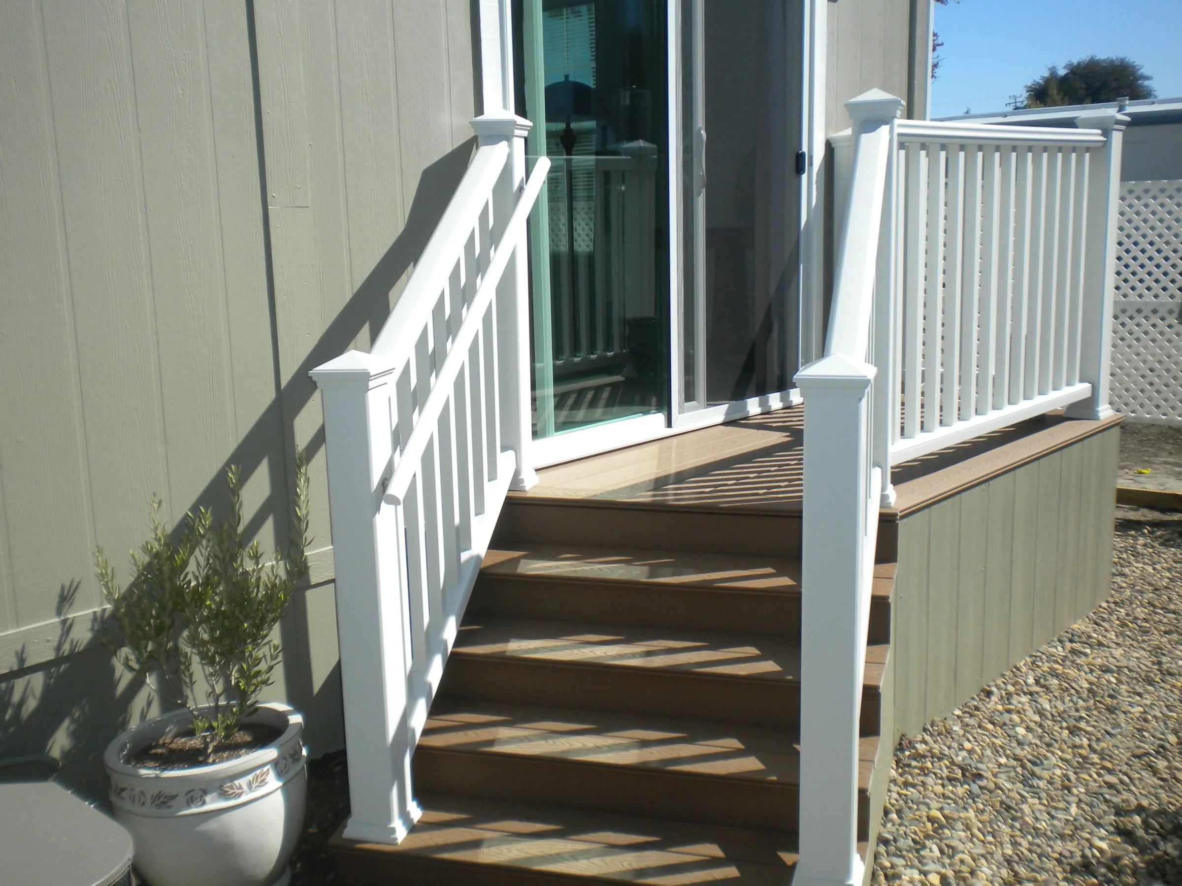 Composite stairs with white railings leading to a mobile home door