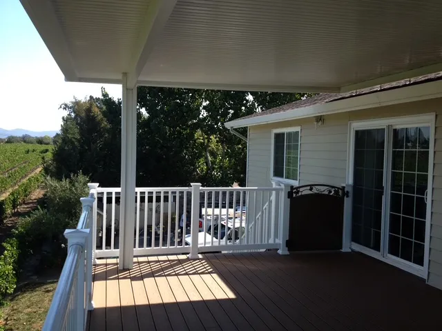 Covered composite deck with white railings beside vineyards