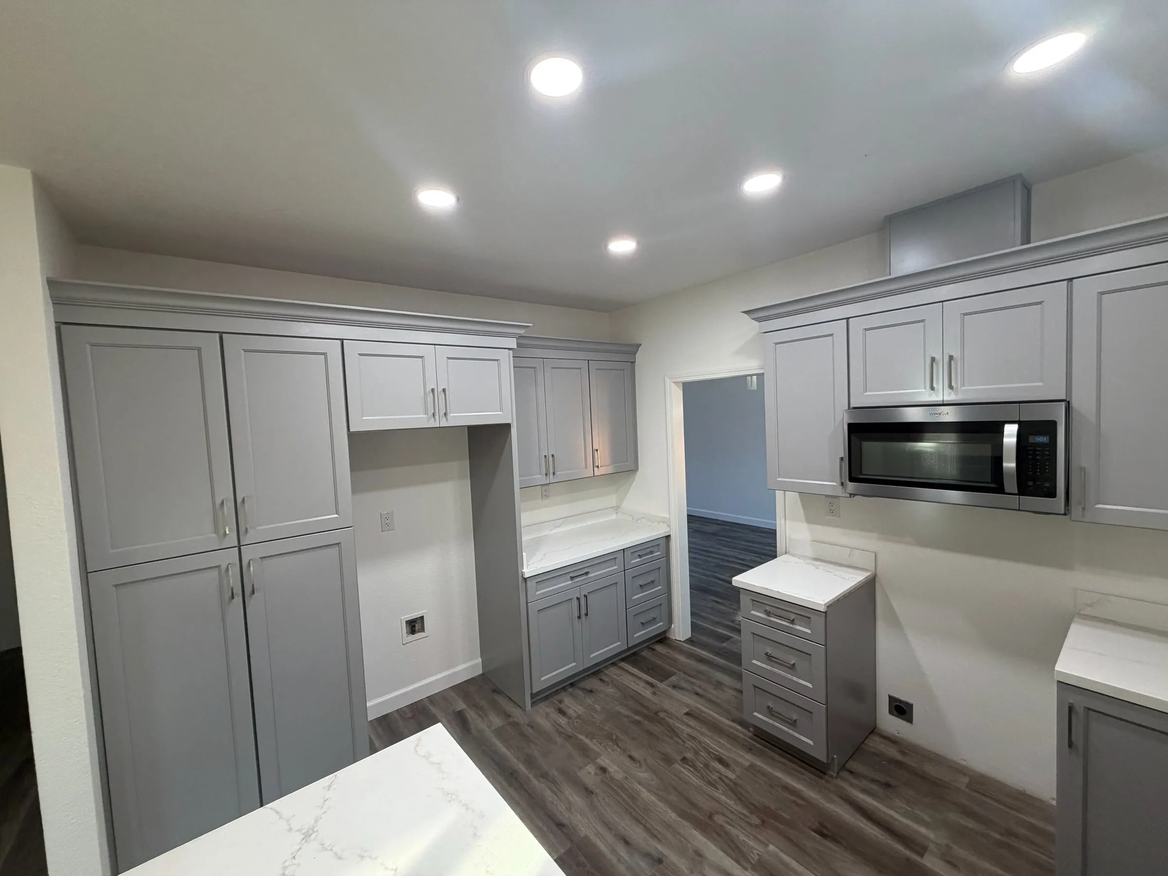 Kitchen remodel with tall gray pantry cabinets, quartz counters and recessed lighting