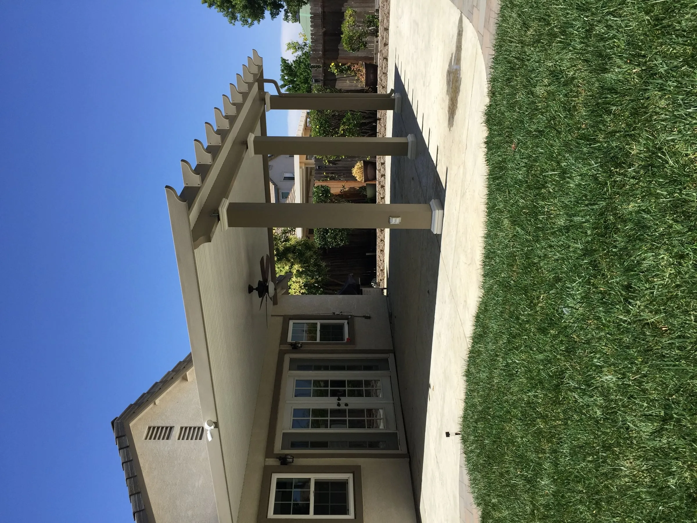 Patio cover with lattice edges and a ceiling fan outside French doors