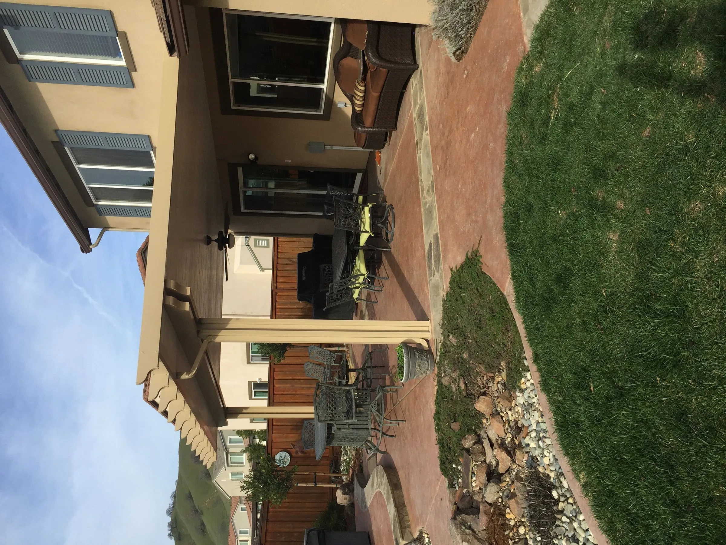 Tan patio cover with lattice edges over a paver patio and lawn