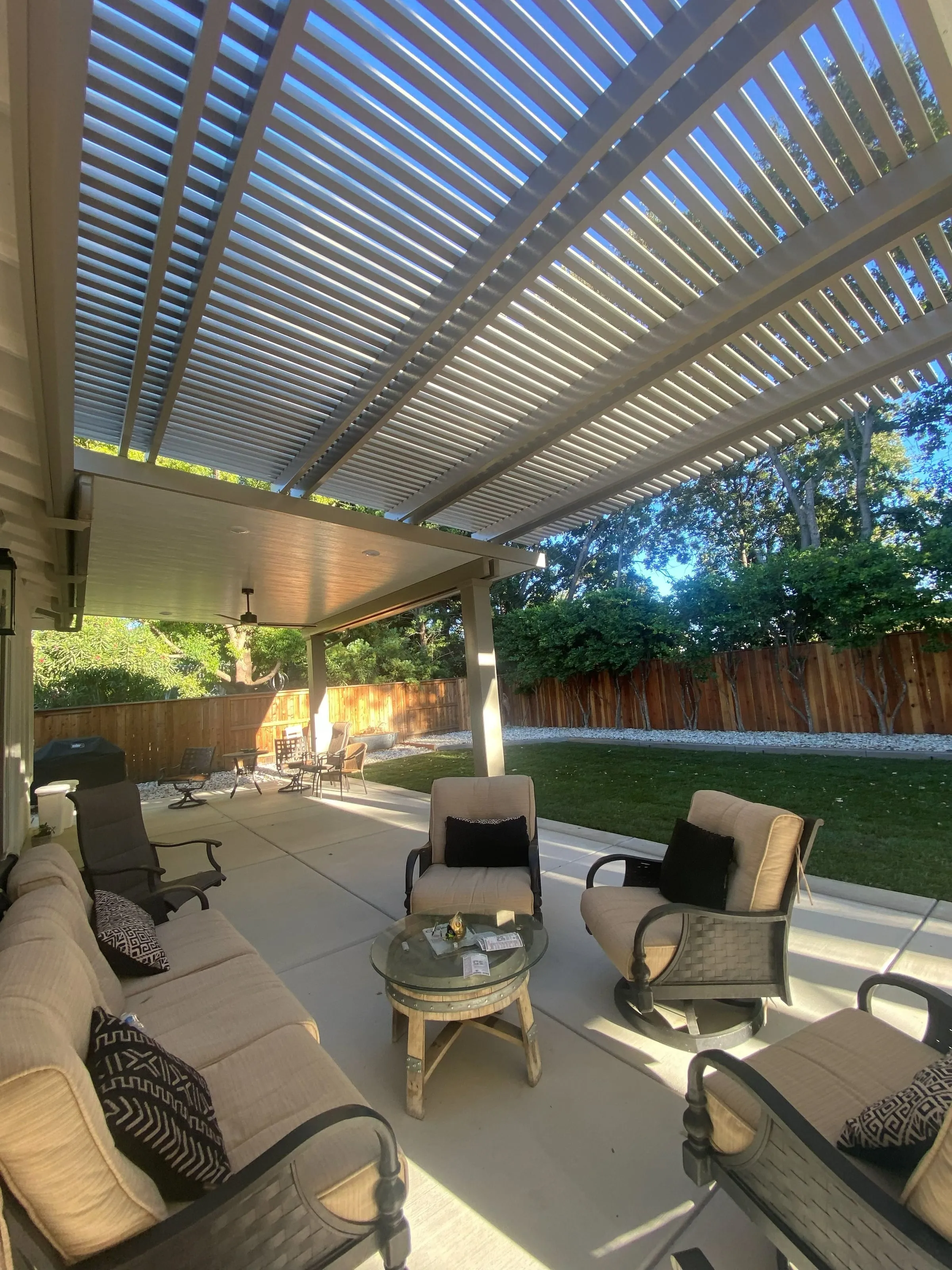 Louvered patio cover over a seating area with wicker chairs