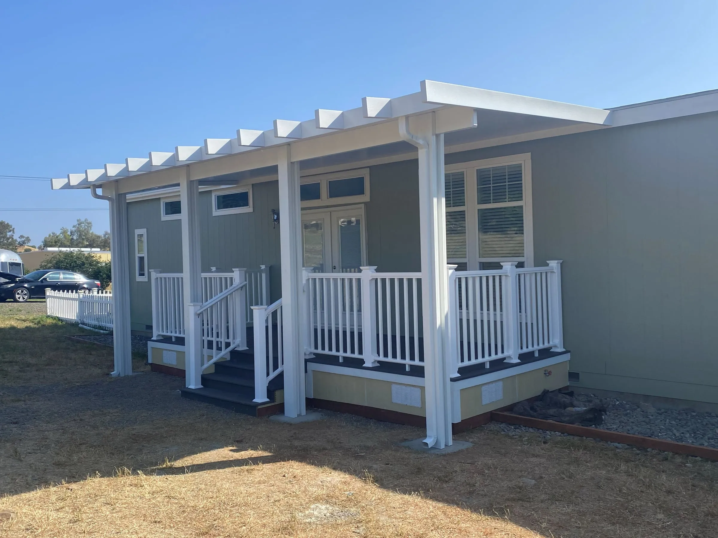 Mobile home deck with white railings under a lattice-edged patio cover