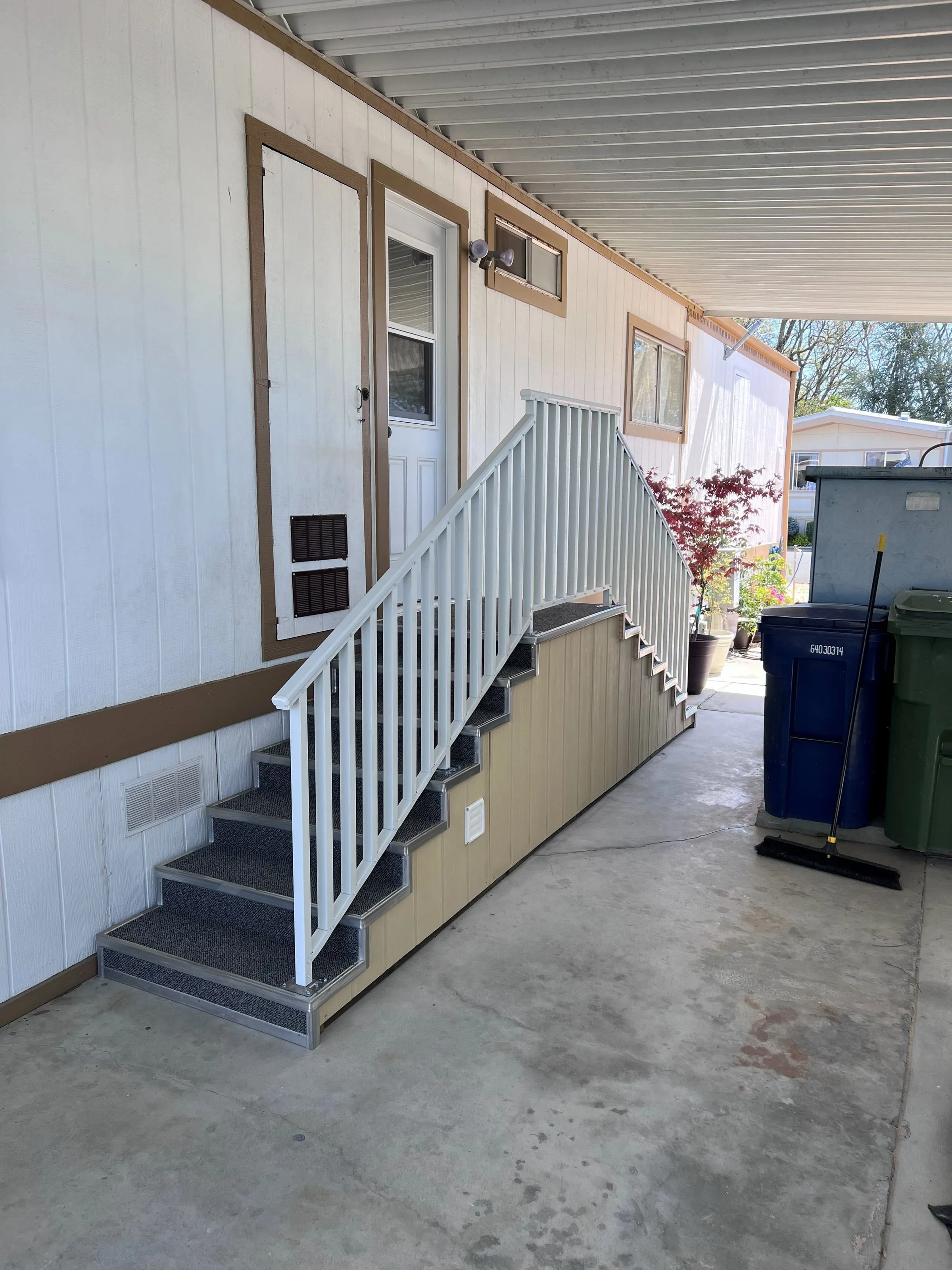 Covered mobile home entry stairs with white handrails