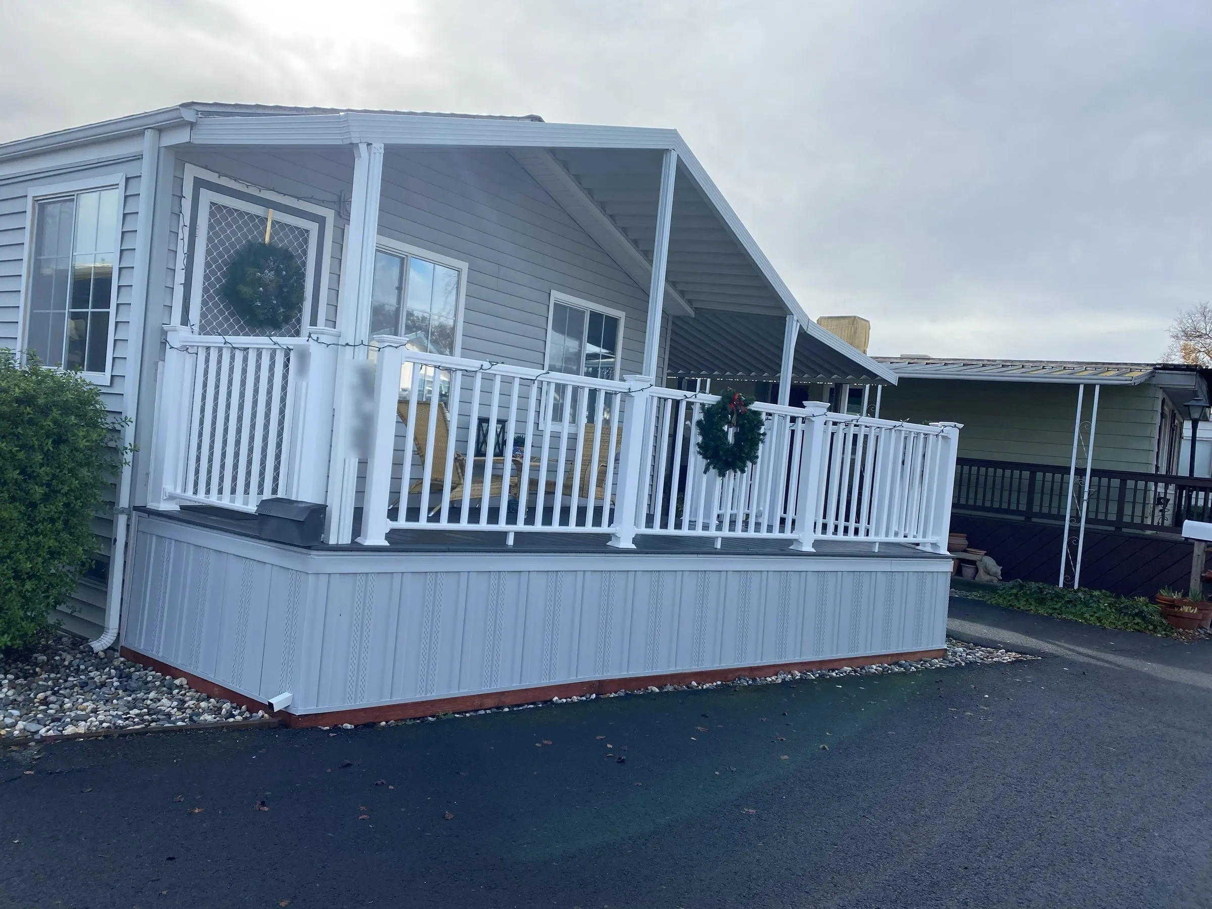 Mobile home with a covered porch deck and white railings