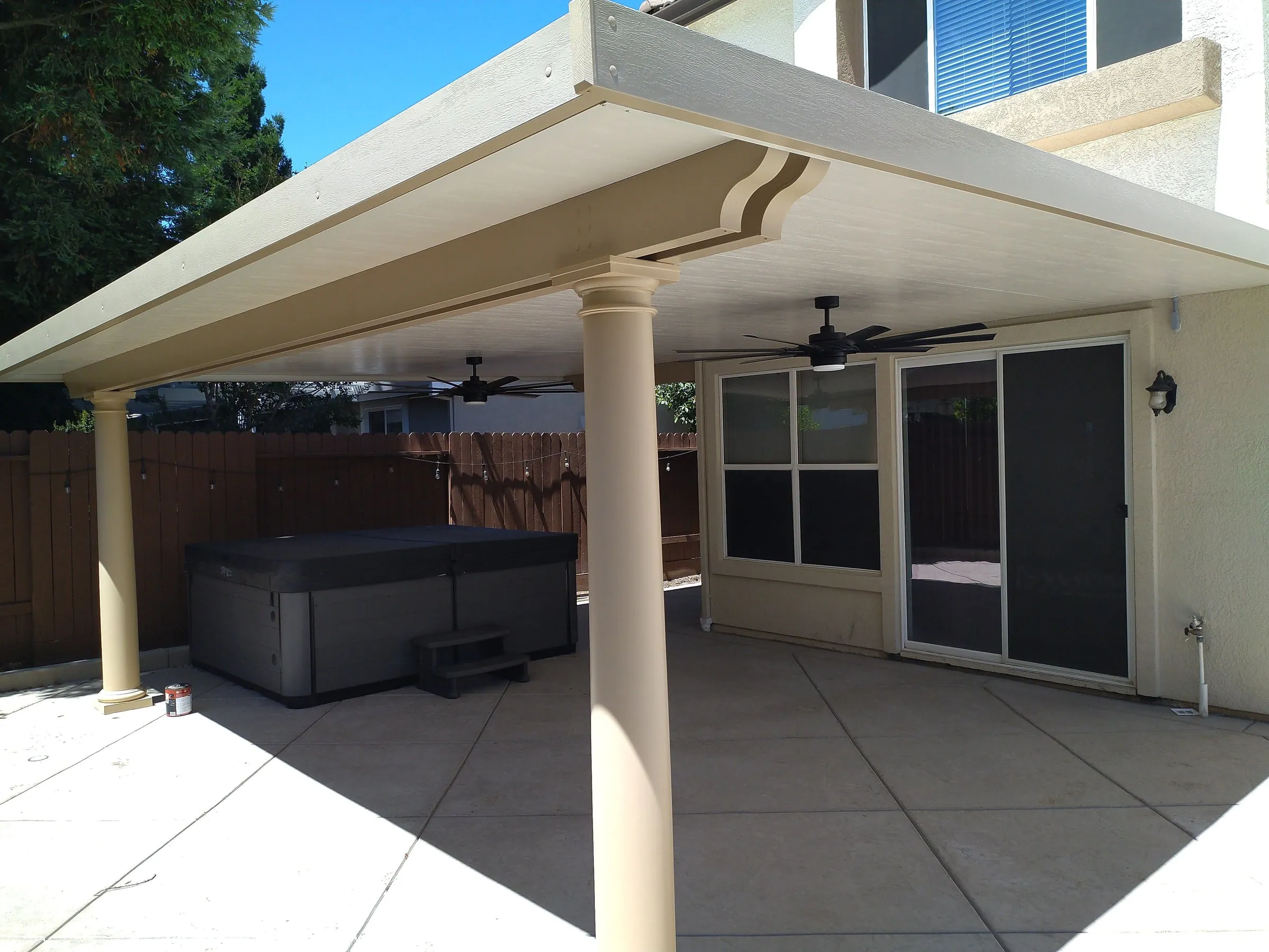 Insulated patio cover with ceiling fans sheltering a hot tub