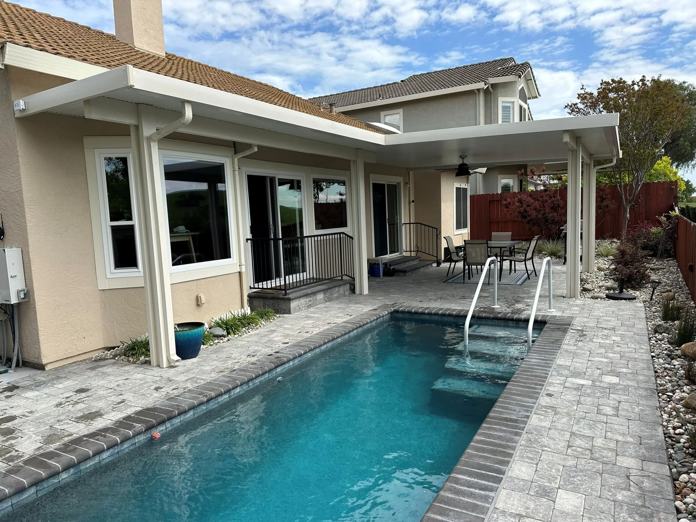Patio cover along the back of a home beside a narrow lap pool