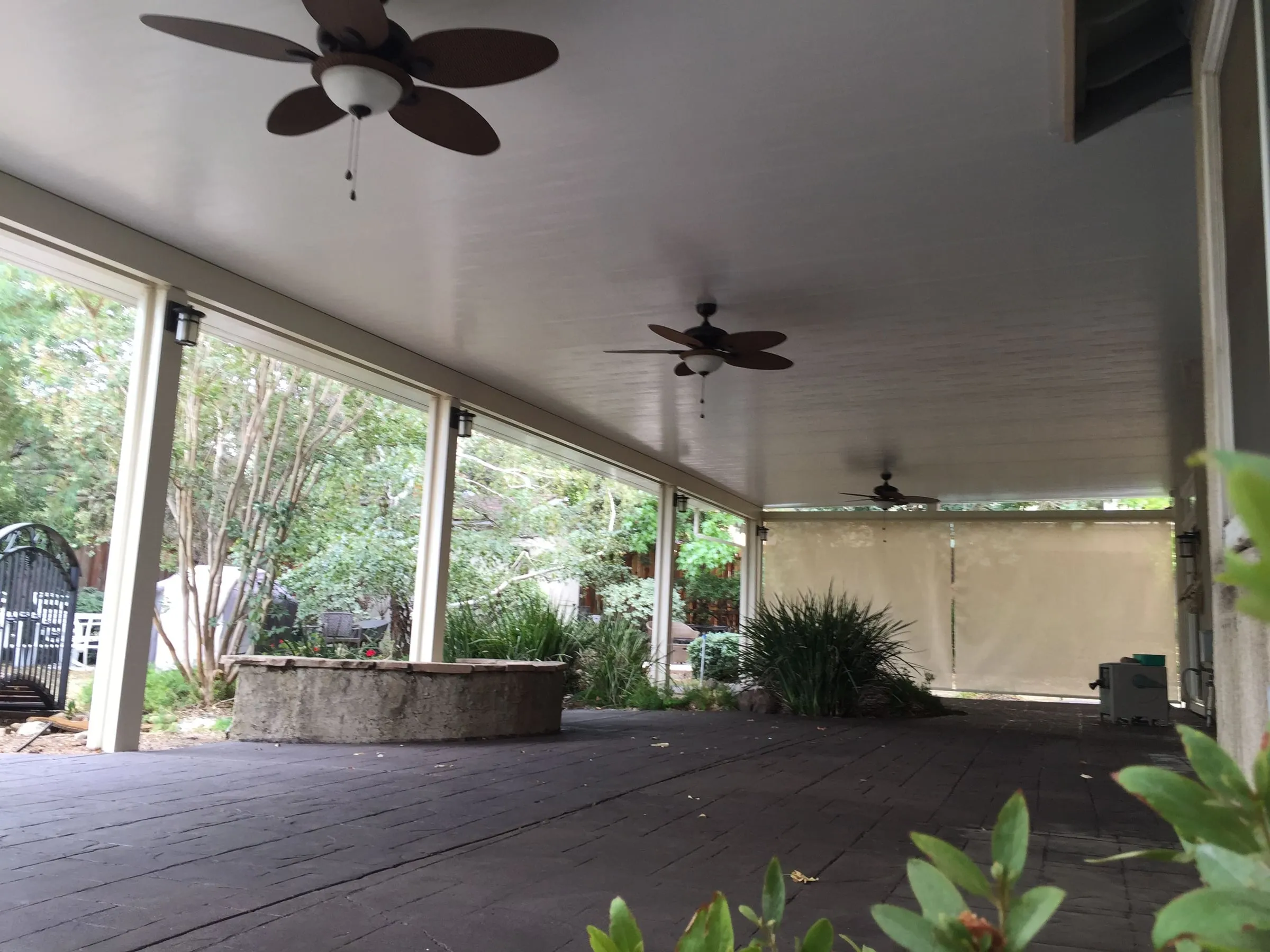 Under a patio cover with ceiling fans and roll-down shade screens