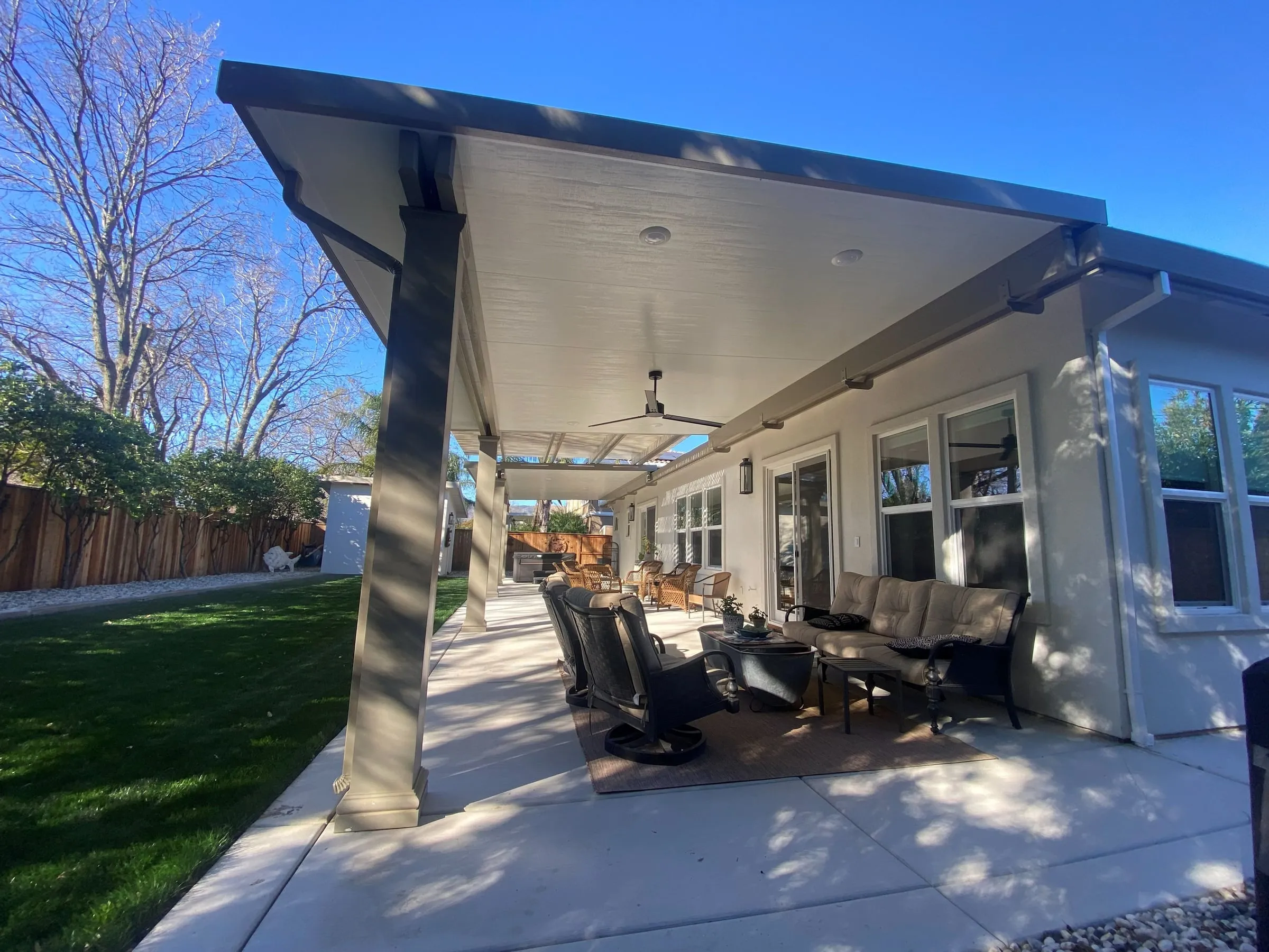 View under a long insulated patio cover with ceiling fans over outdoor seating