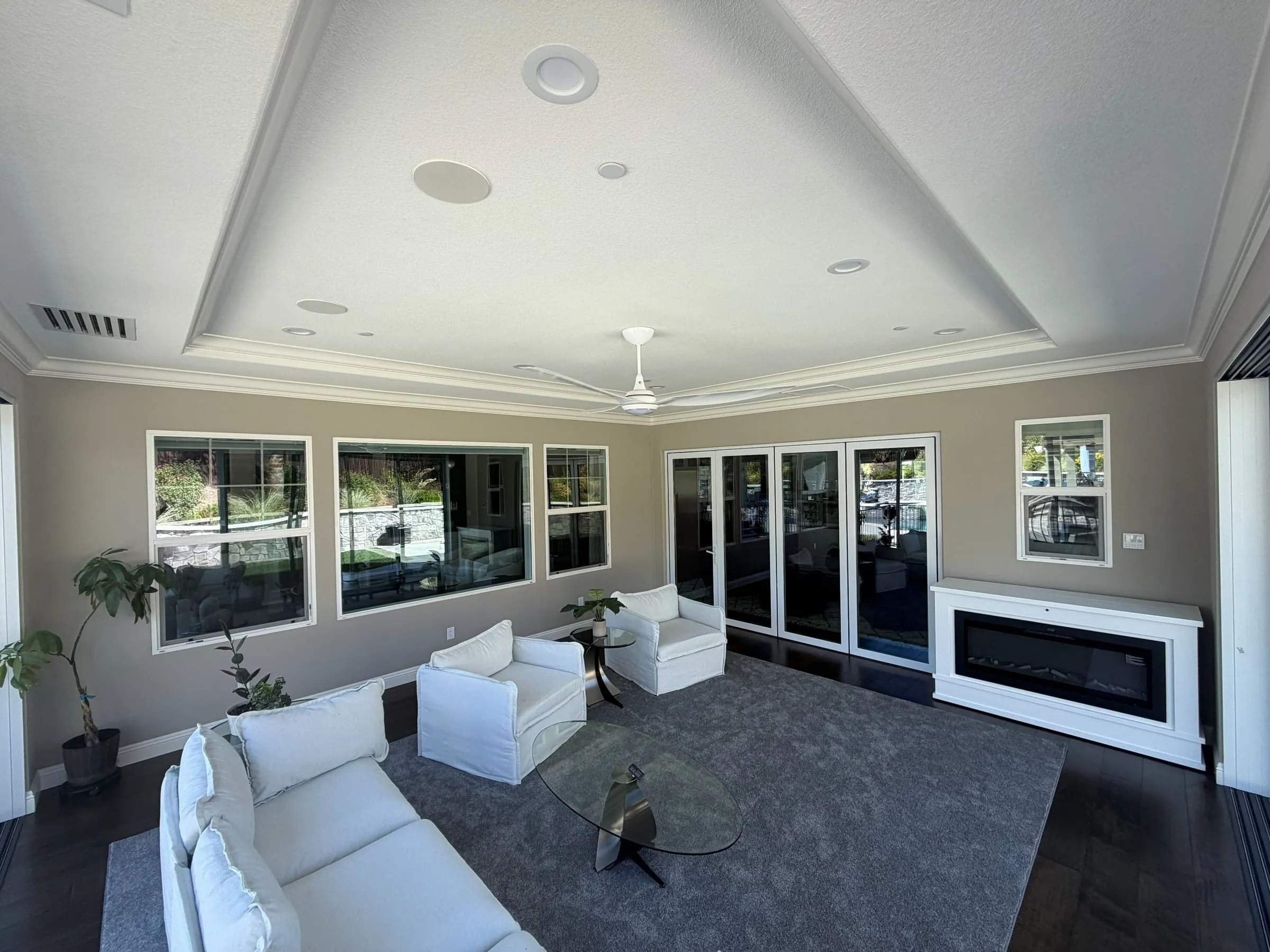 Finished room addition with a tray ceiling, wall fireplace and large windows