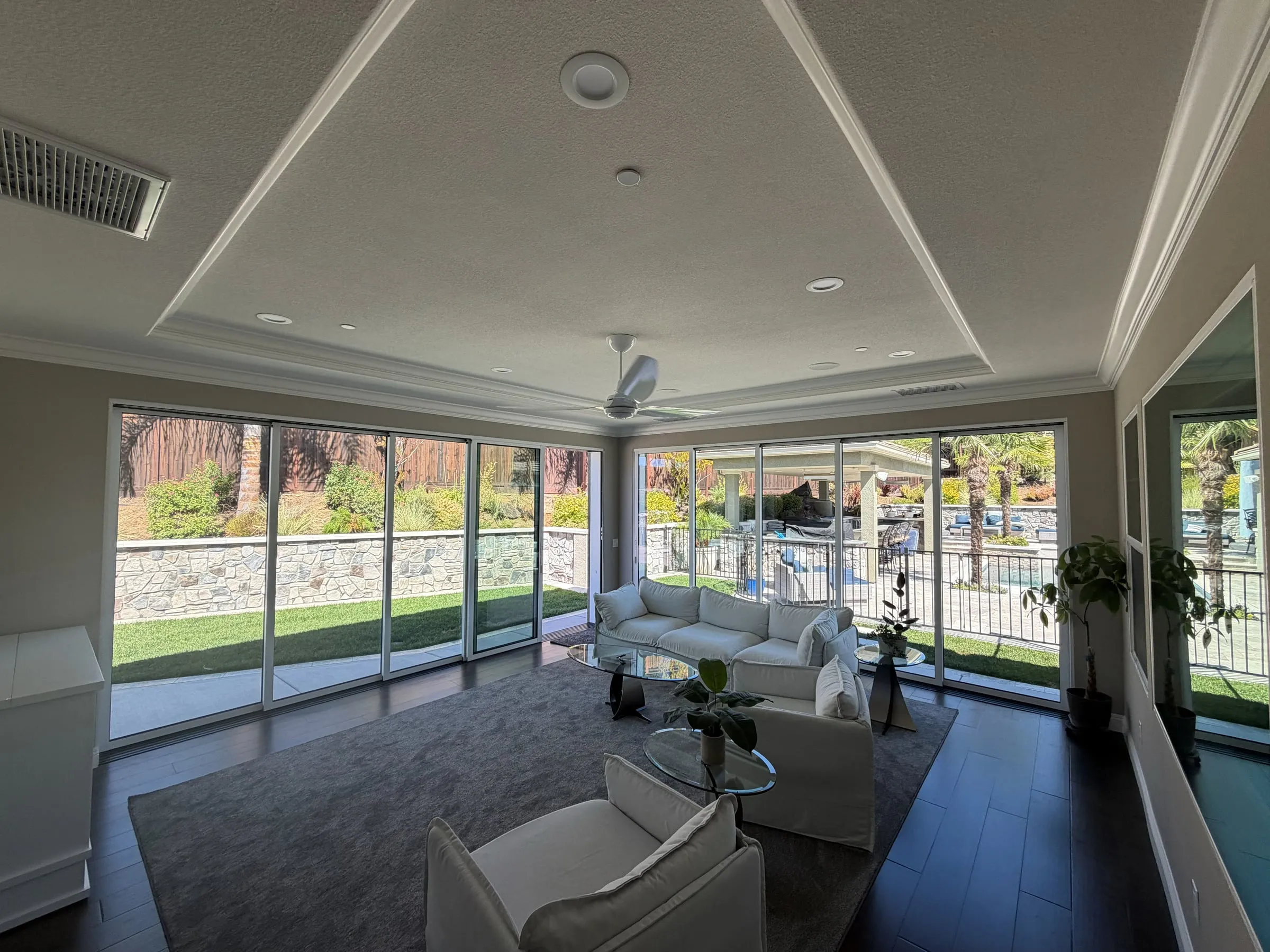 Inside a finished room addition with a tray ceiling, recessed lights and a wall of glass doors