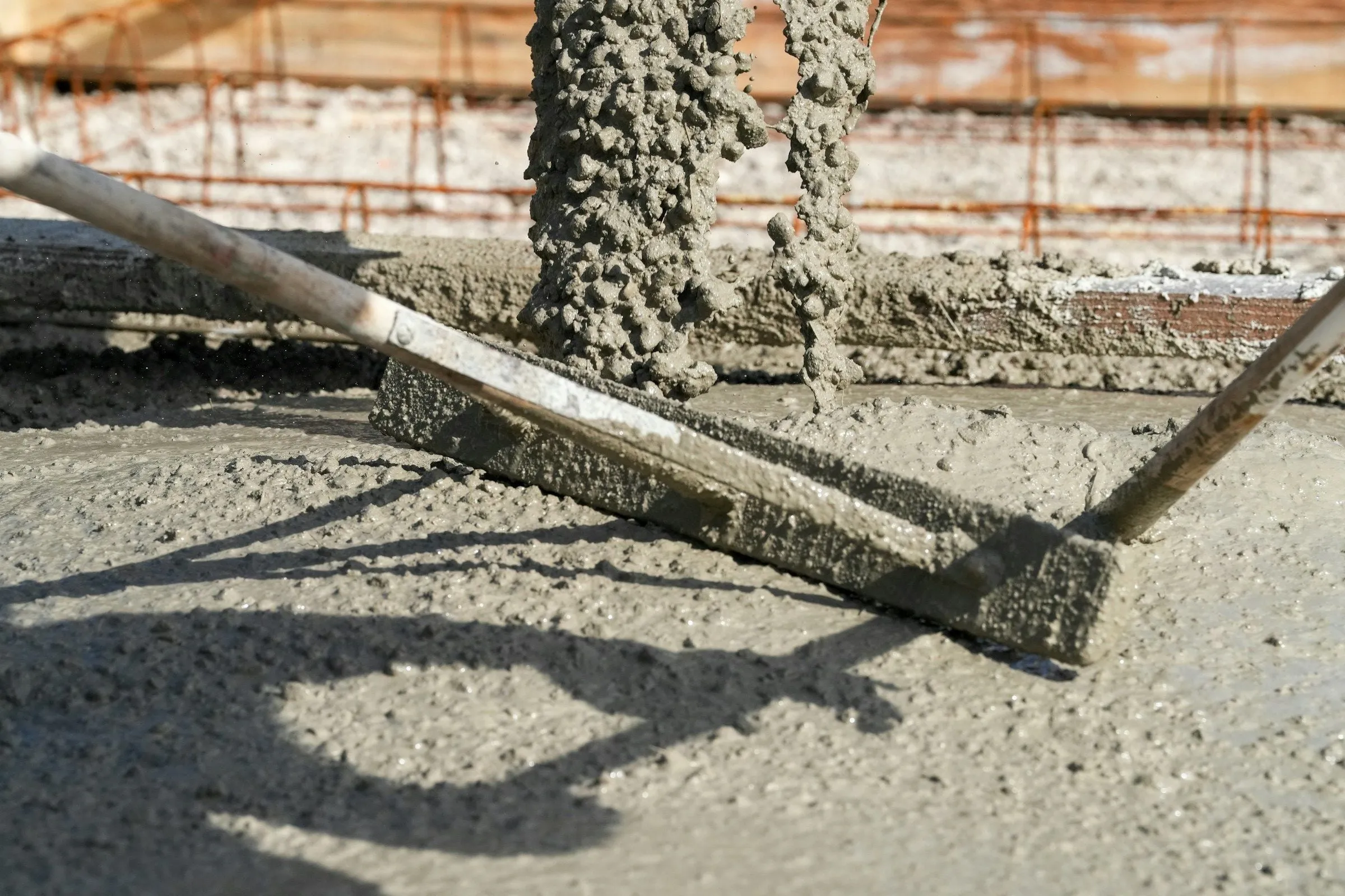 Fresh concrete being poured and leveled with a screed board