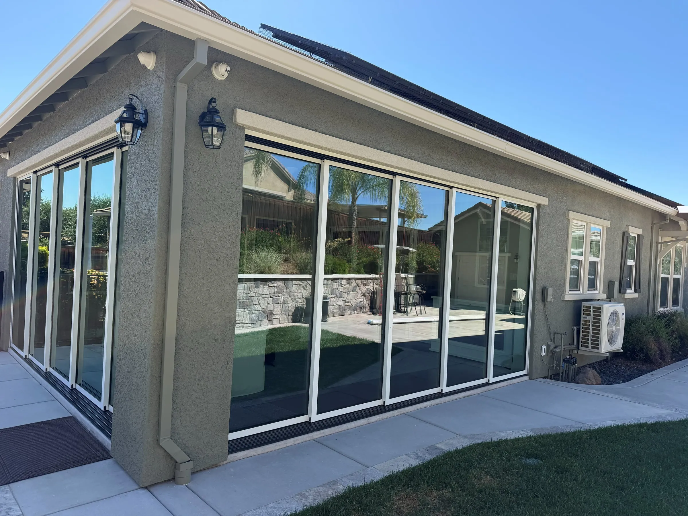 Stucco room addition with folding glass walls, lantern lights and a new walkway