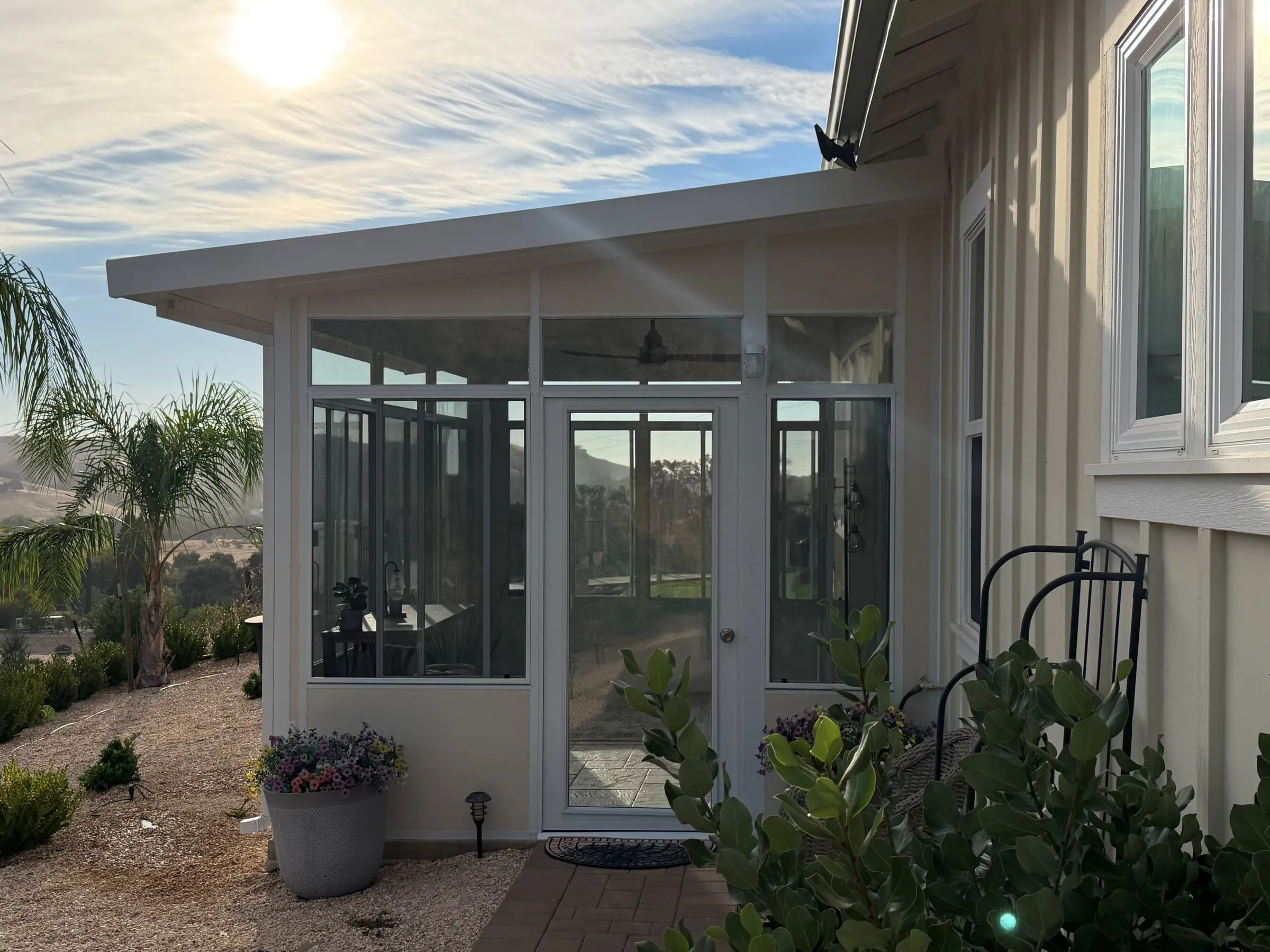 Sunroom addition with a glass door and wide windows facing the hills