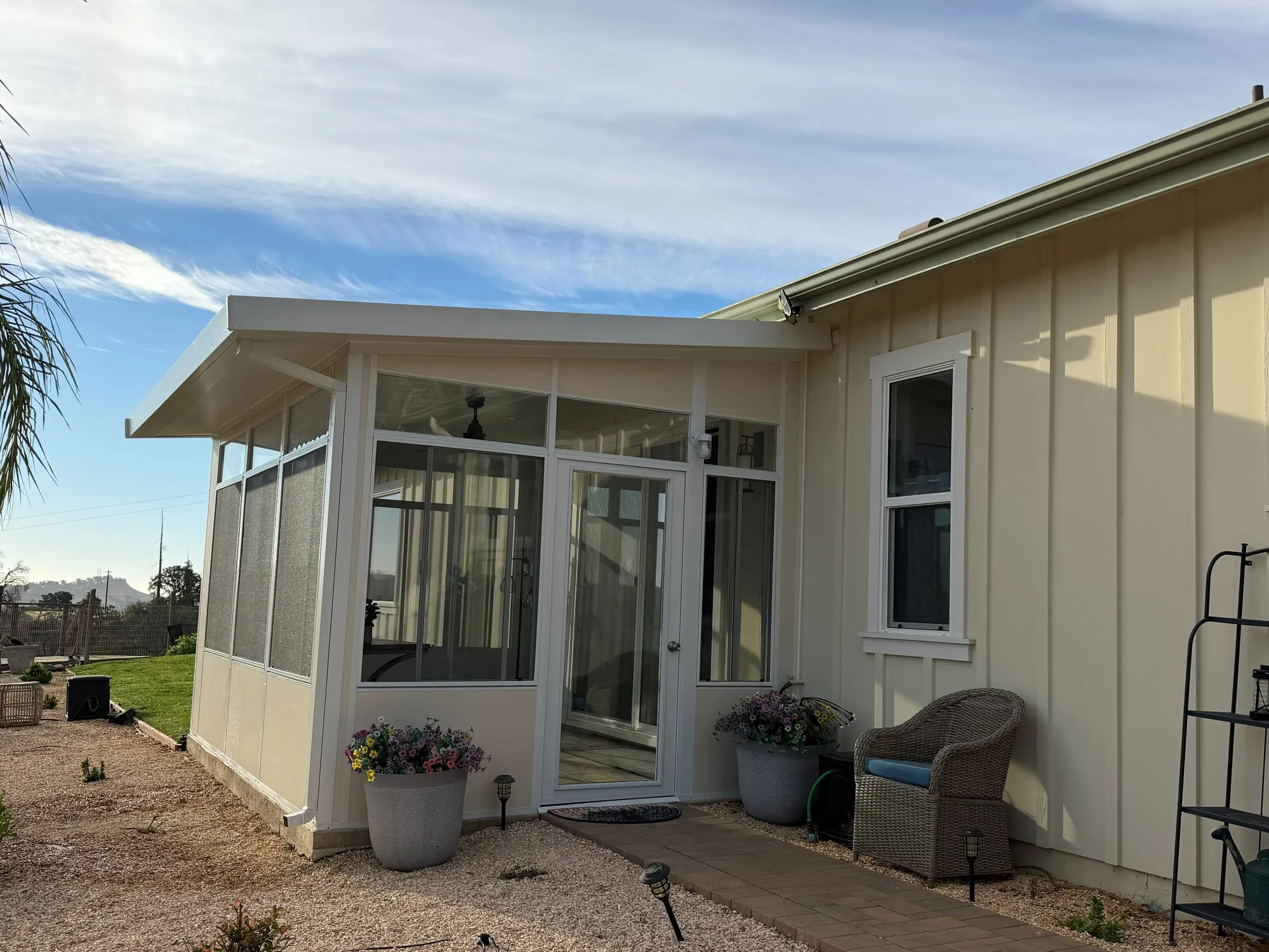 Sunroom with a glass entry door, screened windows and a paver walkway