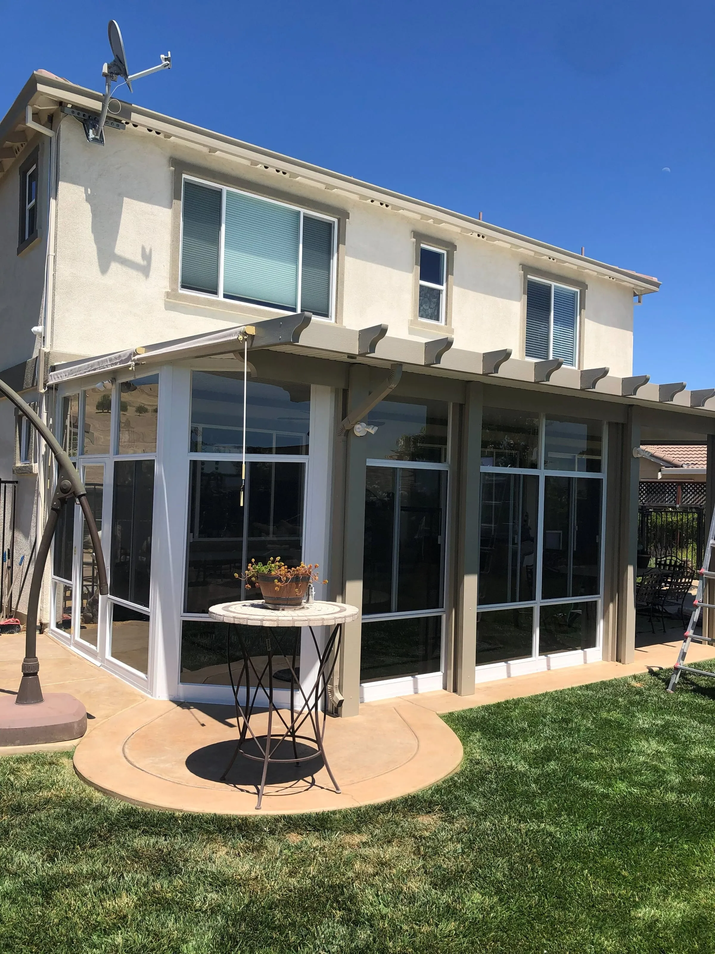 Glass sunroom with a lattice-edged roof on the back of a two-story home